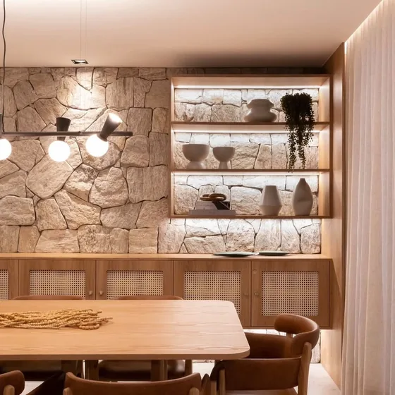 Sala de jantar com parede de pedra e nichos iluminados