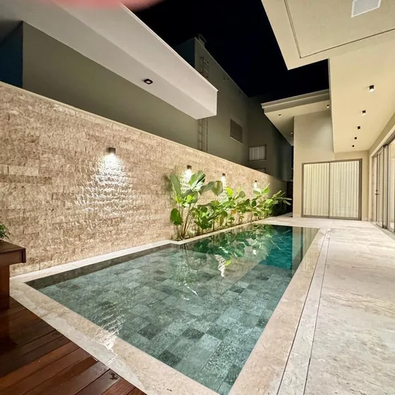 Área de lazer com piscina e parede em pedra natural