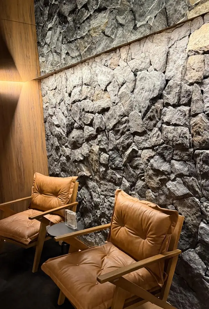 Parede em Pedra Black com poltronas de couro
